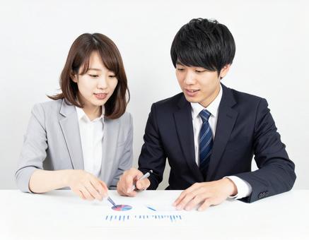 データを見ながら打ち合わせる男女社員 データを見ながら打ち合わせる男女社員の写真