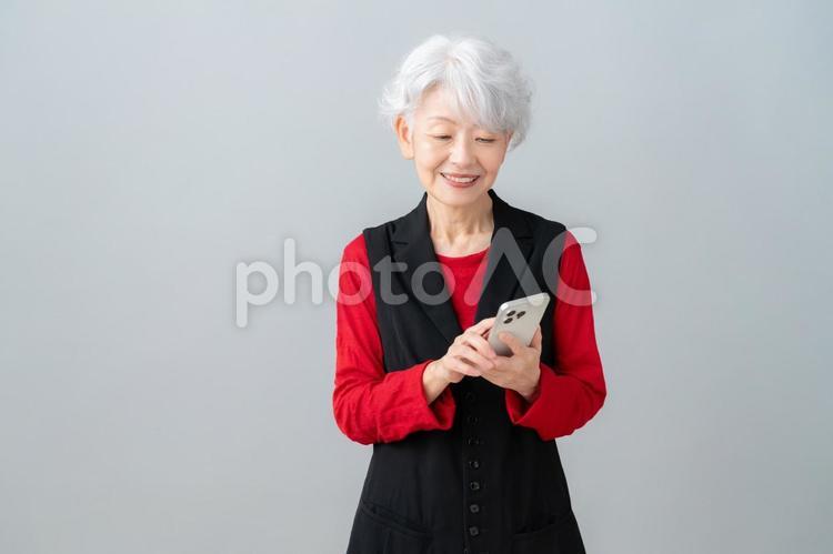 スマホを見るグレーバックのシニアの女性 シニア,女性,スマホの写真素材