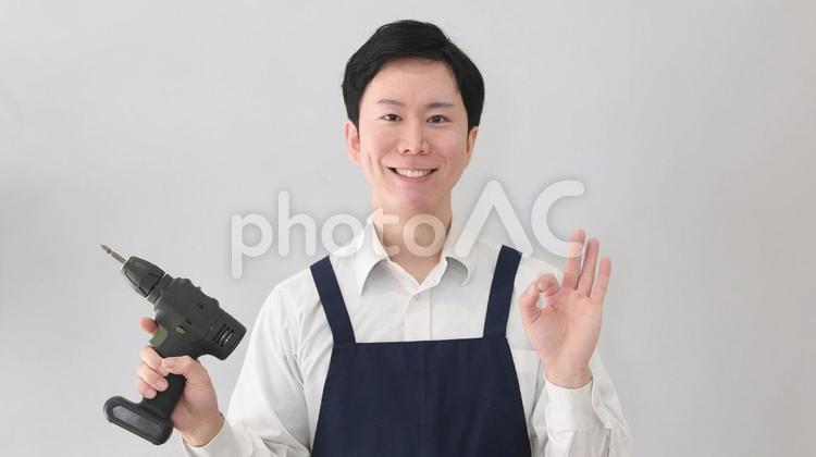 工具を持ちOKサインをするアジア人の男性 エプロン,男性,電動ドリルの写真素材