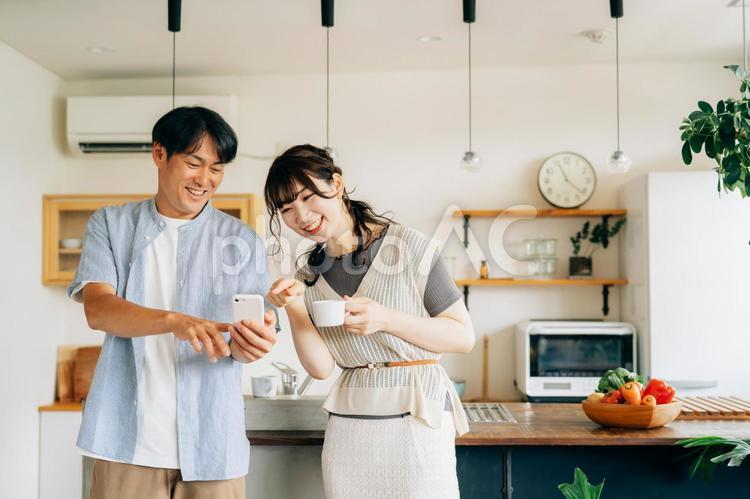 キッチンの前でスマホを使う男女 スマホ,夫婦,スマートフォンの写真素材