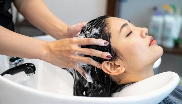 美容院でシャンプーされる女性の写真