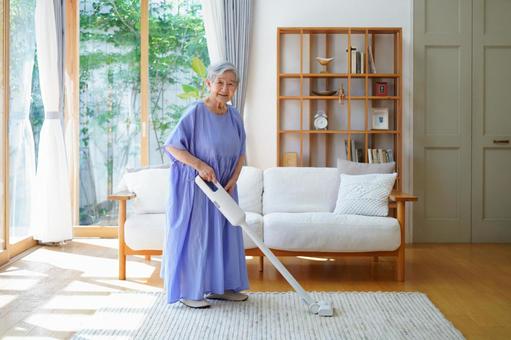 笑顔でラグの掃除をする青い服の女性 女性,掃除,掃除機の写真素材