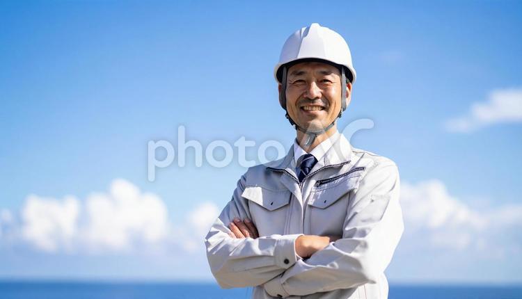 青空の下で笑顔の日本人若い男性建設作業員 作業服,男性,若いの写真素材