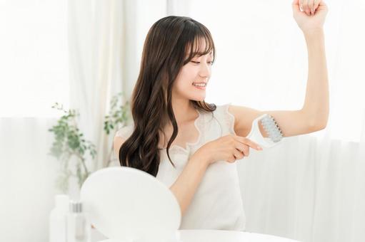 家で腕にマッサージローラーを使う若い女性 家で腕にマッサージローラーを使う若い女性の写真