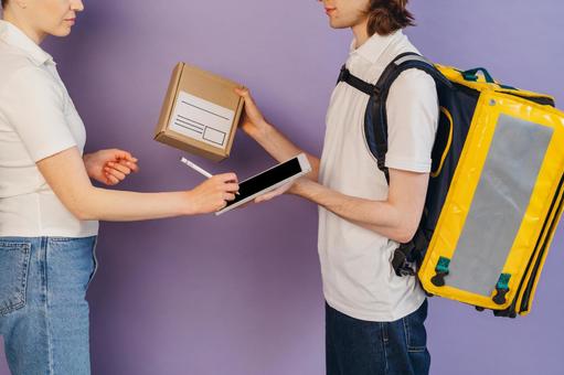 受取サインをする女性と配達員の男性 配達,デリバリー,配送の写真素材