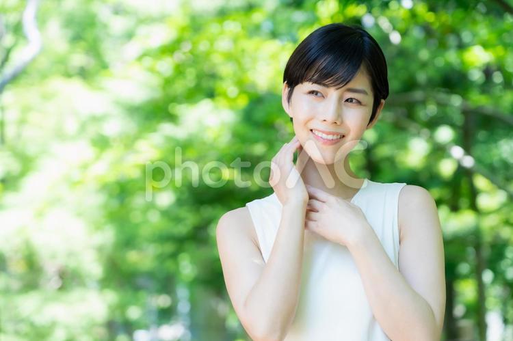 緑の中でスキンケアをする若い女性 スキンケア,ビューティー,女性の写真素材