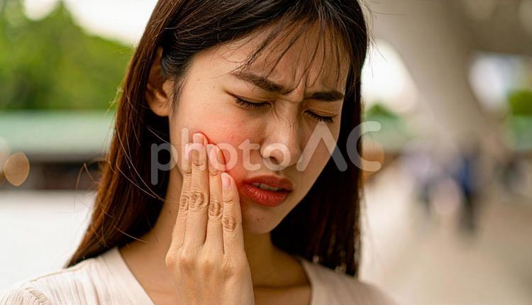 歯が痛んで手で押さえる女性 患部,歯茎,20代の写真素材