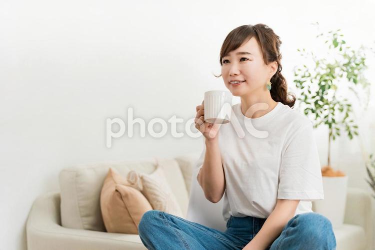 ソファに座ってドリンクを飲む日本人女性 お茶,白湯,飲むの写真素材