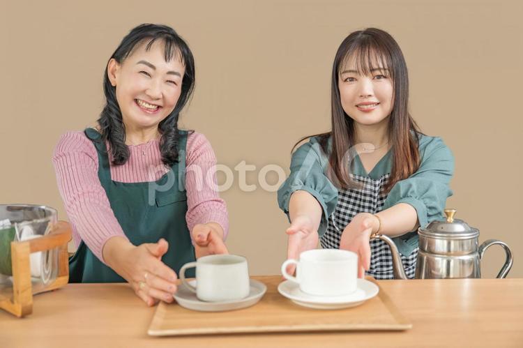 カフェで珈琲を出す2人 カフェ,笑顔,エプロンの写真素材