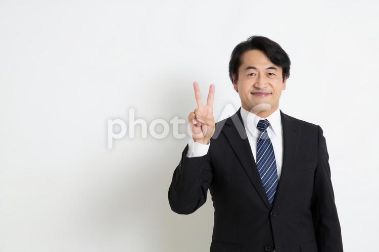 笑顔で指を2本立てている中年のサラリーマン男性（コピースペース） 中年,上司,会社員の写真素材