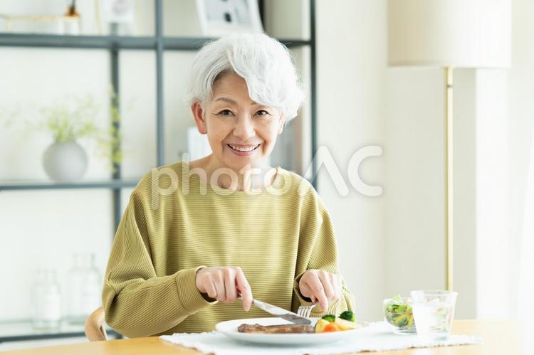 ステーキを食べるシニアの女性 ステーキ,食事,牛肉の写真素材