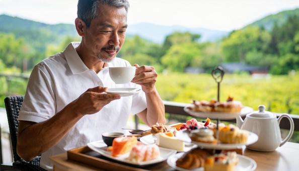 紅茶とお菓子でティータイムを楽しむ男性 紅茶とお菓子でティータイムを楽しむ男性の写真
