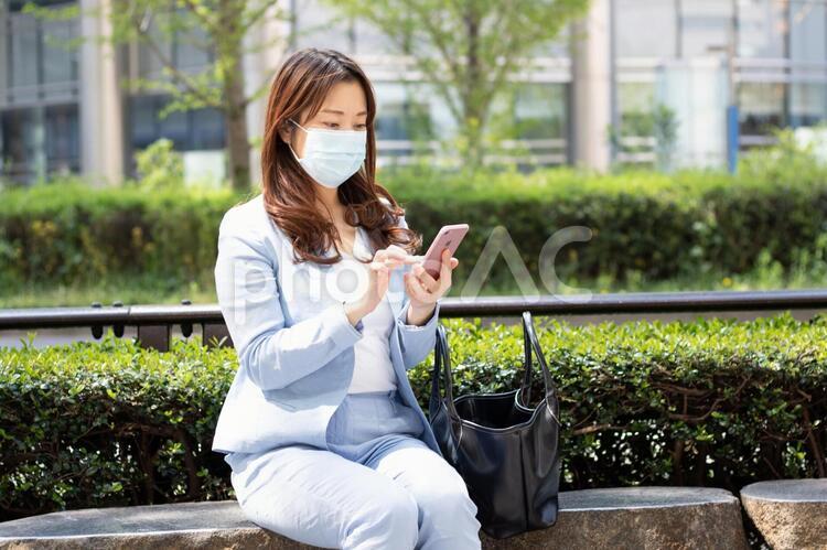 マスクをしてスマホを見る女性 女性,スーツ,olの写真素材