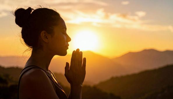 夕焼けに手を合わせて祈る女性 夕焼けに手を合わせて祈る女性の写真