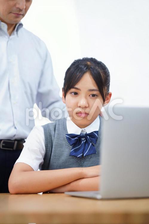 ノートパソコンを見ている制服を着た女の子 人物,男性,お父さんの写真素材