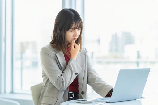 パソコンを使いながら考える女性 女性,パソコン,考えるの写真素材