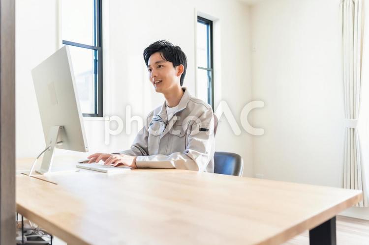 パソコン作業をする作業着を着た男性 男性,ビジネス,ビジネスマンの写真素材