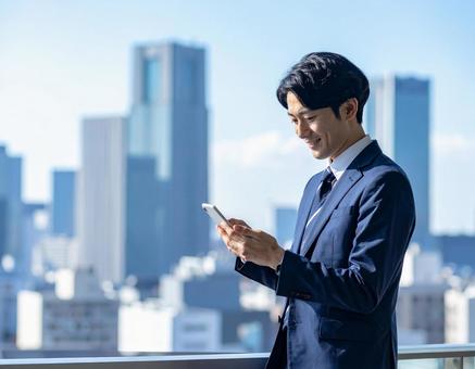 スマホを見るビジネスマン スマホを見るビジネスマンの写真