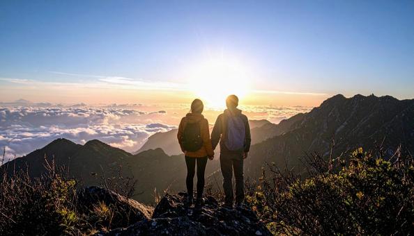 山から朝日を眺める日本人カップル 山から朝日を眺める日本人カップルの写真