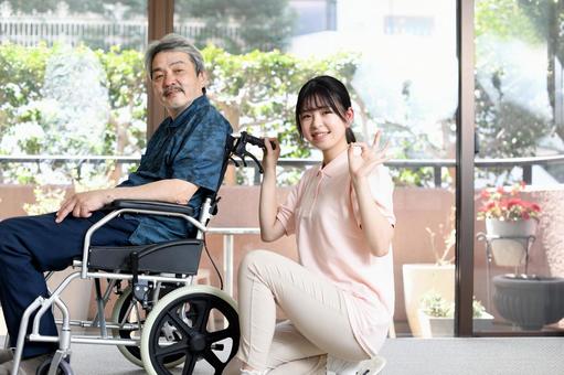 車椅子に乗る高齢者男性と若い女性の介護士 車椅子に乗る高齢者男性と若い女性の介護士 介護,介護士,介護職の写真素材