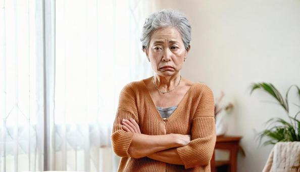 腕組みして機嫌の悪い高齢女性の写真