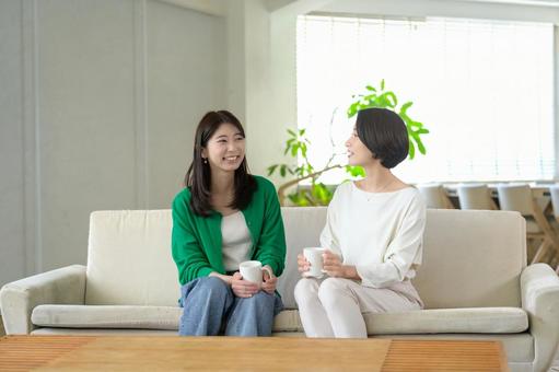 ソファに座って笑い合う日本人女性 ソファに座って笑い合う日本人女性 おしゃべり,リビング,友達の写真素材