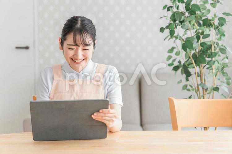 タブレットPCを使うエプロン姿の女性 タブレット,介護士,介護福祉士の写真素材
