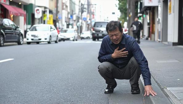 胸を押さえ苦しむ男性 胸を押さえ苦しむ男性の写真