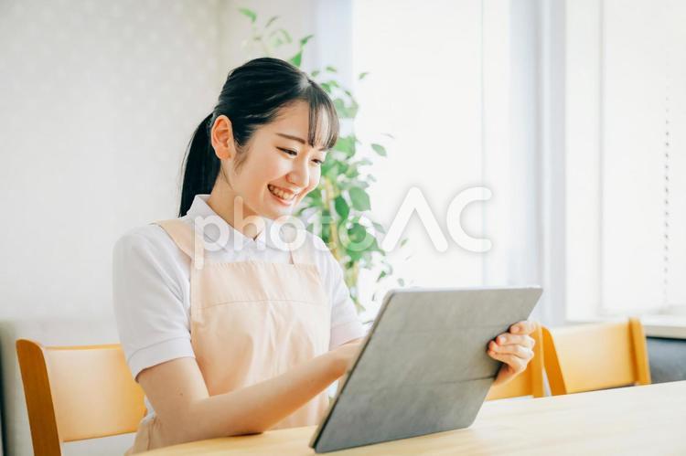 タブレットPCを使うエプロン姿の女性 タブレット,介護士,介護福祉士の写真素材