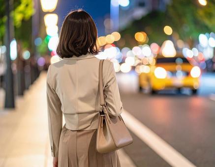 残業終わりにタクシーを待つ女性会社員 残業終わりにタクシーを待つ女性会社員の写真