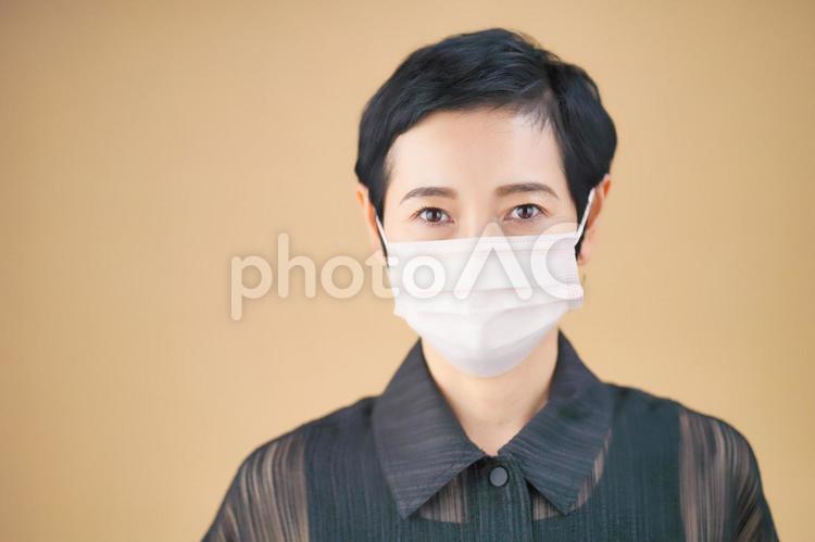 マスクをしたショートカットの女性（ベージュ背景） 女性,日本人,50代の写真素材