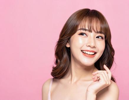 美容系の女性モデル　笑顔　ピンク背景2の写真