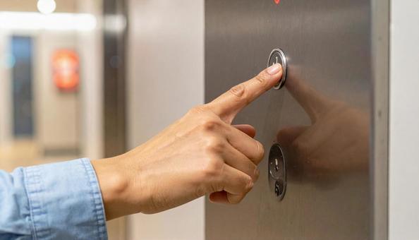 エレベーターのボタンを押す女性の手の写真