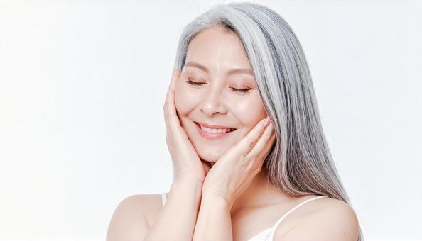 目を閉じて頬を撫でる笑顔のシニア女性の写真