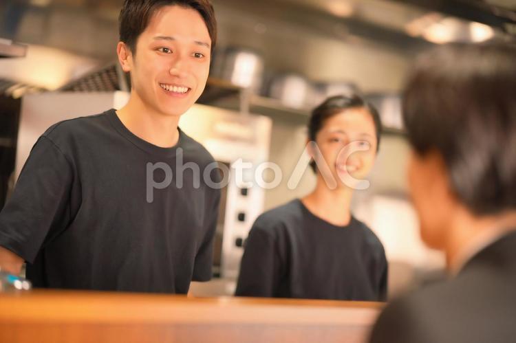 カウンター越しに話す男性店員たち 男女,大学生,話すの写真素材