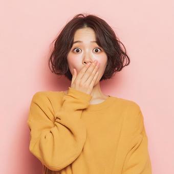 驚きで口元を覆う若い日本人女性 驚きで口元を覆う若い日本人女性の写真