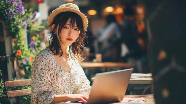 緑豊かなカフェでノートPCを使用する女性の写真