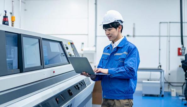 工場の三次元測定機を使う作業服の男性 工場の三次元測定機を使う作業服の男性の写真