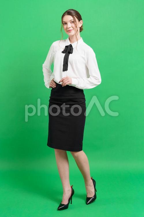 片手を腰に当ててポーズする外国人女性（緑背景） 女性,立つ,ポーズの写真素材