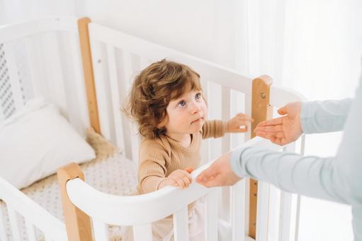 差し出された手の方を見る子供 差し出された手の方を見る子供 赤ちゃん,かわいい,ベビーベッドの写真素材