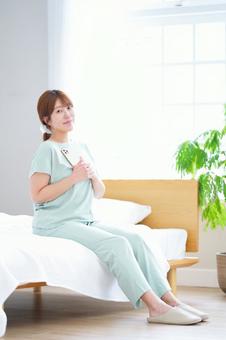 スマホを持ちベッドに座る女性 女性,スマートフォン,持つの写真素材