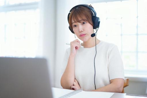 ペンを持ち悩みながらパソコンを見つめる女性 女性,ヘッドセット,ペンの写真素材