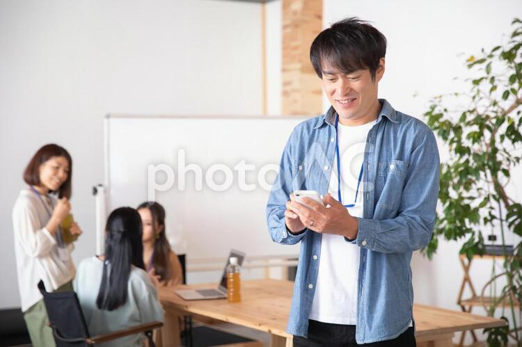 スマホを持つカジュアルな服装のビジネスマン アプリ,スマホ,スマートフォンの写真素材