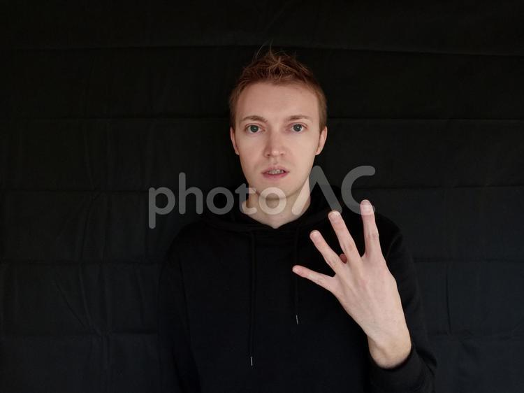 4をジェスチャーで表している外国人男性　黒バック 四,4,よんの写真素材