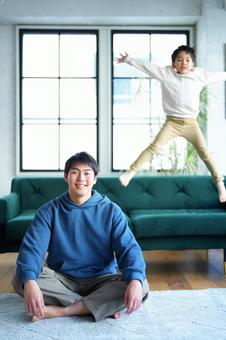 あぐらで座る男性とジャンプする男の子 あぐらで座る男性とジャンプする男の子の写真