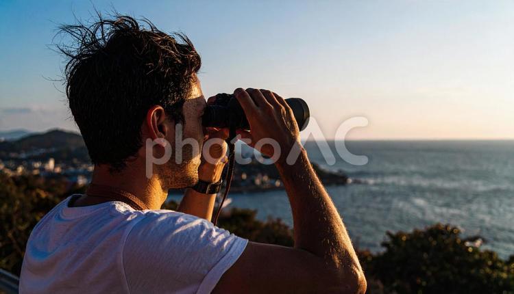 双眼鏡で海の先を見ている日本人男性 双眼鏡,見通し,未来の写真素材