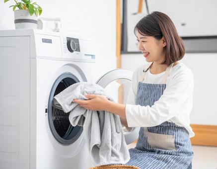 洗濯機からタオルを取り出す若い日本人女性 洗濯機からタオルを取り出す若い日本人女性の写真