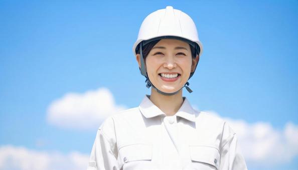 青空の下で笑顔の作業服を着た若い女性 青空の下で笑顔の作業服を着た若い女性の写真
