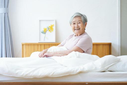 ベッドで微笑むショートヘアのおばあちゃん 女性,ベッド,座るの写真素材