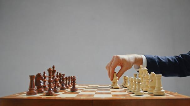 チェスをするスーツ男性の手(グレー背景) チェスをするスーツ男性の手(グレー背景)の写真